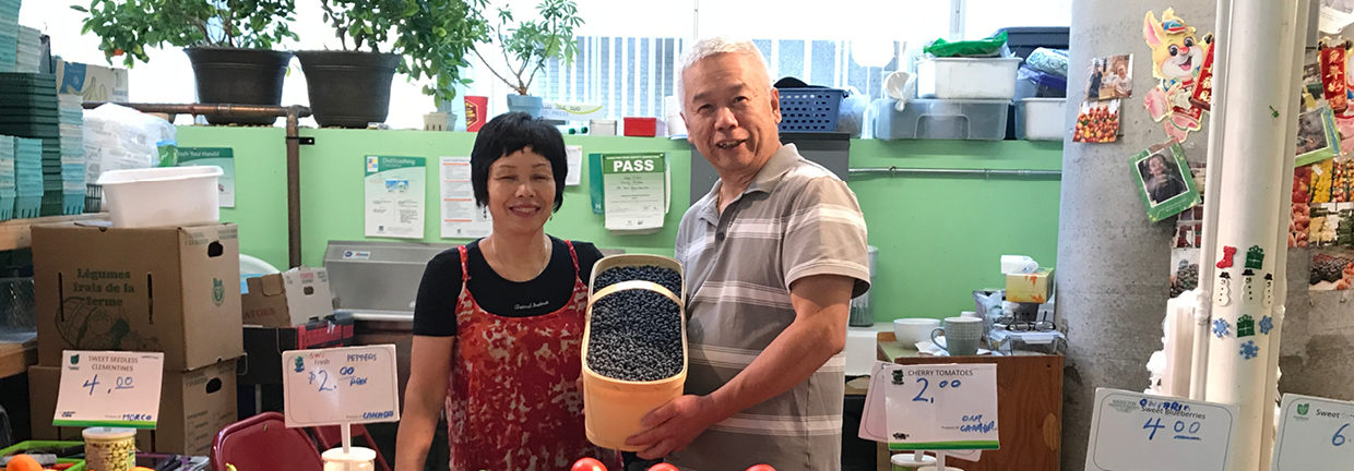 Cau and Chen Hieng pose with a basket of blueberries by their stand in the Market