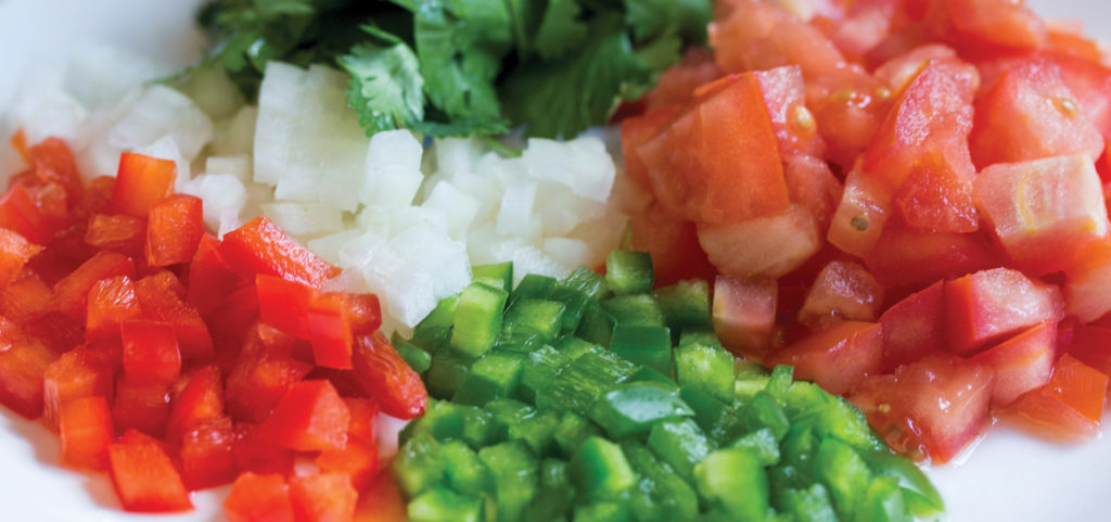 Chopped peppers, tomato, onions on a cutting board
