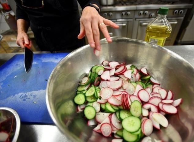 Sliced radishes and cucumber being prepared for a salad